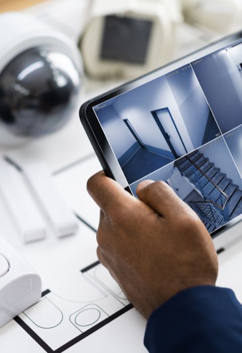 Various CCTV installation components with person holding a tablet showing CCTV footage