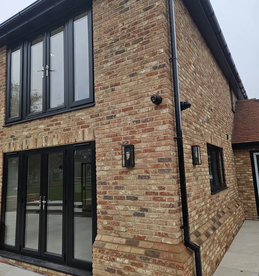 Rear elevation of a Kent home with CCTV covering the patio doors and side approach, the camera sited so it barely reads from the garden